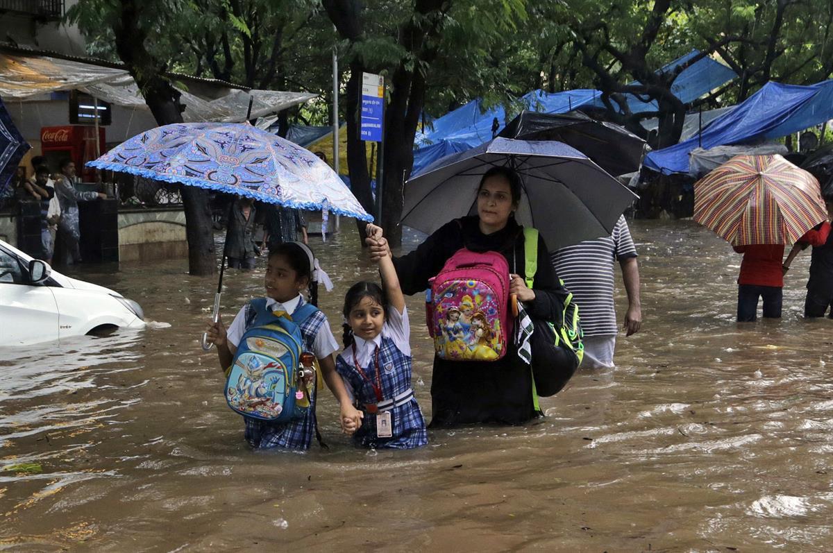 Schoolchildren wade past a waterlogged railway street in the rain in Mumbai, India — Tuesday, Aug. 29, 2017 (AP/Rajanish Kakade, File)