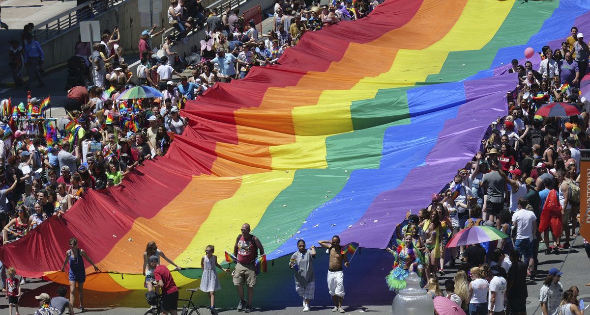 People carry a flag during the Utah Pride parade in Salt Lake City. Salt Lake City police are looking for leads after a man was allegedly attacked while trying to defend two gay men being chased after the Utah Pride Festival. Sunday, June 3, 2018 (AP Photo/Rick Bowmer)