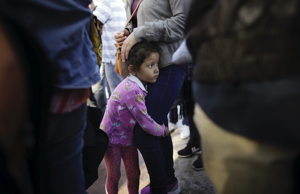 In this June 13, 2018 photo, Nicole Hernandez, of the Mexican state of Guerrero, holds on to her mother as they wait with other families to request political asylum in the United States, across the border in Tijuana, Mexico. The family has waited for about a week in this Mexican border city, hoping for a chance to escape widespread violence in their home state. (AP Photo/Gregory Bull)