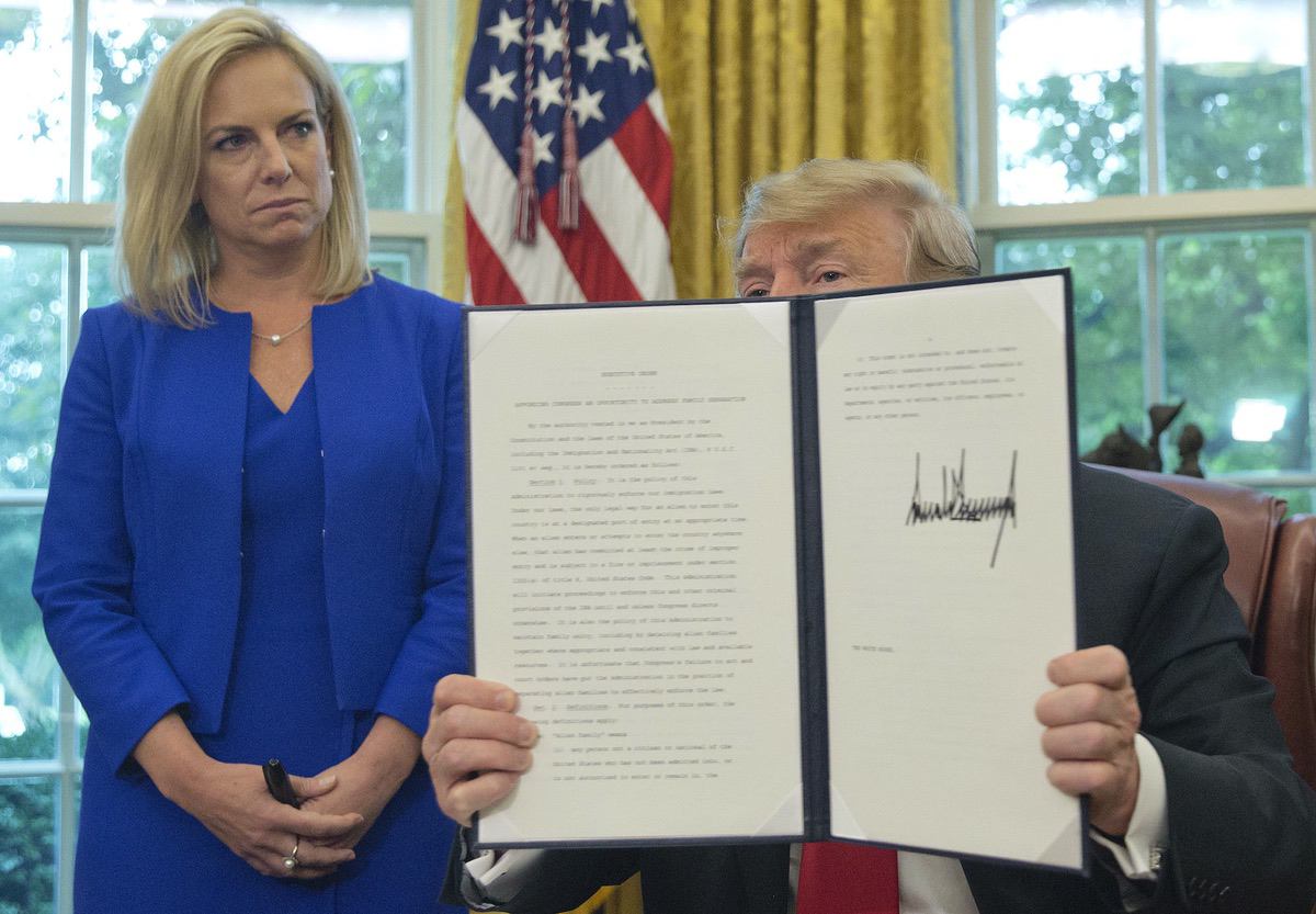 President Donald Trump holds up an executive order he signed to end family separations, during an event in the Oval Office of the White House in Washington, Wednesday, June 20, 2018. Looking on is Homeland Security Secretary Kirstjen Nielsen, left. (AP Photo/Pablo Martinez Monsivais)