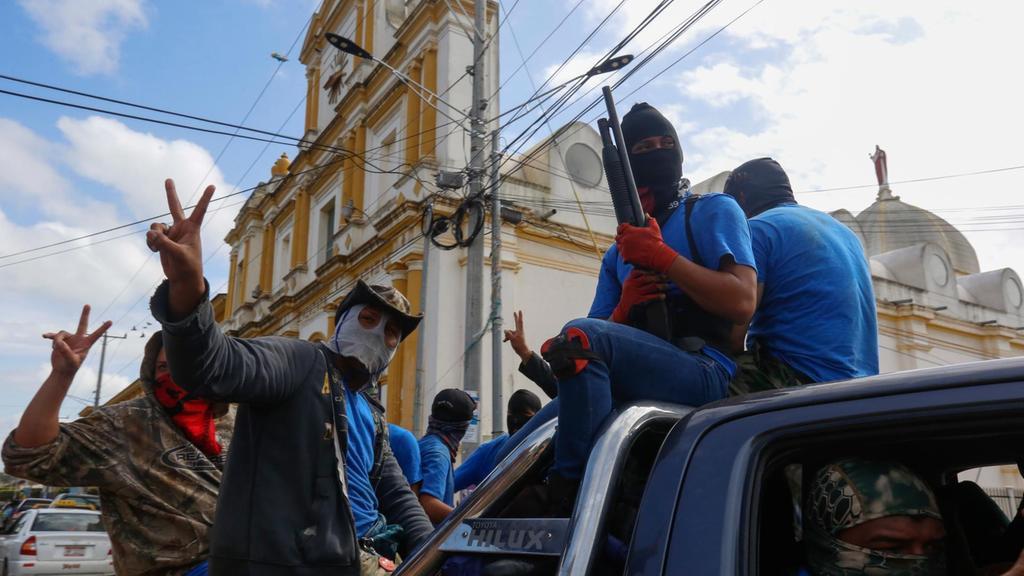 Armed pro-government militia members flash victory signs as they occupy the Monimbo neighborhood of Masaya, Nicaragua, Wednesday, July 18, 2018. (AP Photo/Alfredo Zuniga)