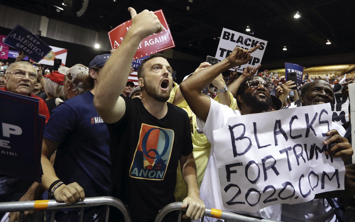 Supporters of President Donald Trump, including one with a QAnon shirt, shout down a CNN news crew before a rally Tuesday, July 31, 2018, in Tampa, Fla. (AP Photo/Chris O'Meara)
